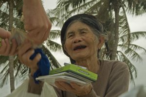 A chewing gum vendor with black-painted teeth